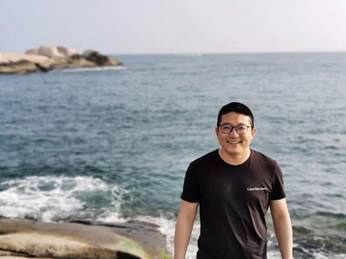 男人拿着冲浪板站在海边 描述已自动生成